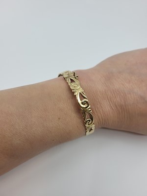 Lot 218 - A 9CT YELLOW GOLD HINGED BANGLE, of open...