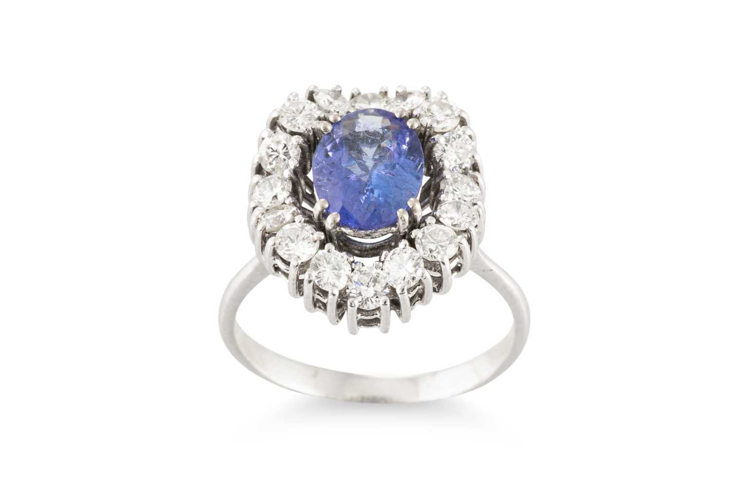 Lot 182 - A TANZANITE AND DIAMOND CLUSTER RING, the oval...