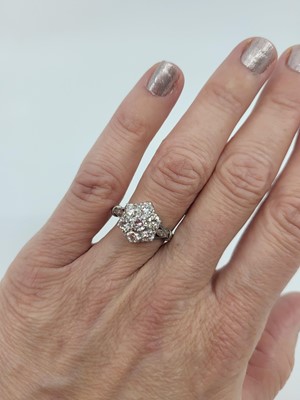 Lot 104 - A DIAMOND DAISY CLUSTER RING, the round...