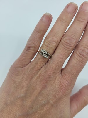 Lot 115 - A FOUR-STONE DIAMOND RING, of cross-over form,...