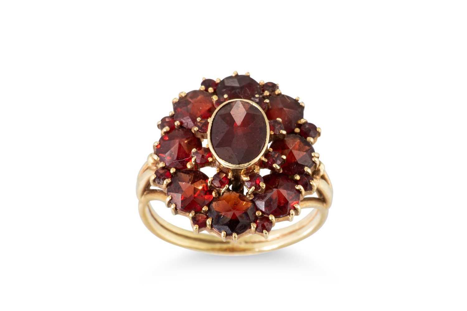 Lot 56 - A GARNET SET CLUSTER RING, the central oval...