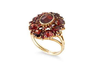 Lot 56 - A GARNET SET CLUSTER RING, the central oval...